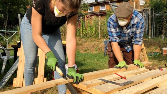 Eine Frau sägt eine Holzlatte © NDR Foto: Jan Baumgart
