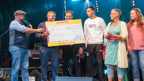 Stefan Kuna übergibt einen riesigen Scheck von Lotto Mecklenburg-Vorpommern an den Bürgermeister von Grimmen. © NDR Foto: Jan Baumgart