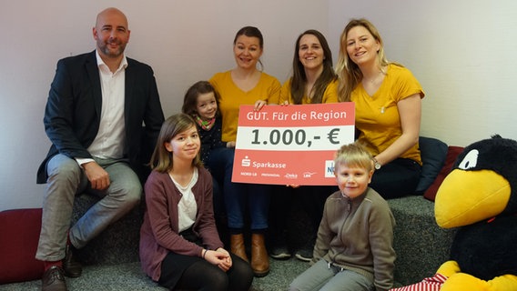 Mitglieder des Vereins LeseMöwe e.V. aus Rostock halten einen Scheck über 1.000 Euro in der Hand. © NDR 