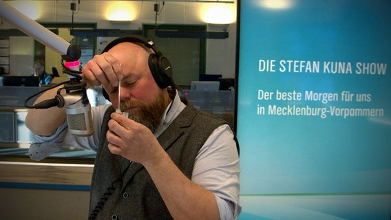 Stefan Kuna macht im Studio von NDR 1 Radio MV einen Corona-Selbsttest aus dem Disounter.  
