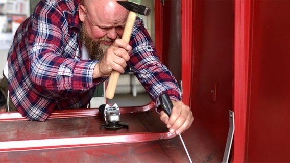 Mit Hammer und Schraubenzieher bearbeitet Reporter Stefan Kuna einen Schlauchwagen. © ndr Foto: ndr