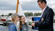 Rasmus und Lina mit Mann bei den Segelbooten © NDR/Romano Ruhnau 