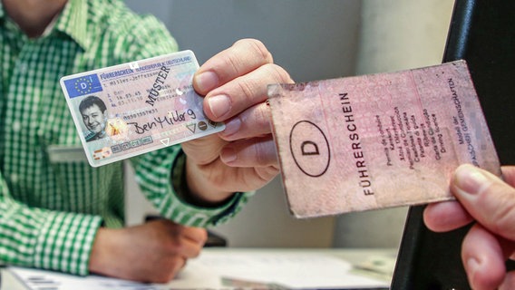 Symbolbild zum Führerschein-Tausch, alt gegen neu: Ein alter Papierführerschein (r.) wird neben einen neuen Muster EU- Führerschein im Scheckkartenformat gehalten. © picture alliance Foto: Andreas Gora