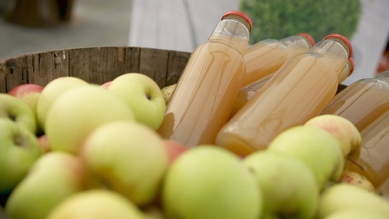 Ein Behälter mit reifen Äpfeln und Apfelsaft-Flaschen © NDR Foto: Udo Tanske
