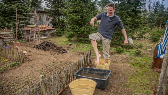 Peter Rasch steigt in einen Eimer voll Wasser. © NDR Foto: Udo Tanske