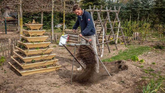 Gartenprofi Peter Rasch siebt Kompost durch ein großes Gartensieb. © NDR Foto: Udo Tanske