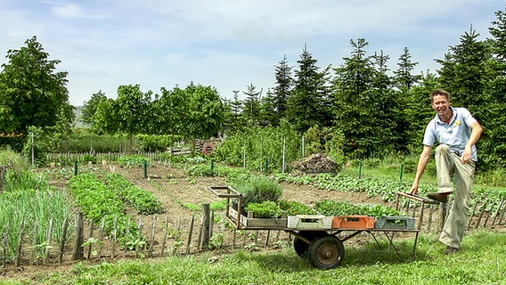 Ein Gärtner steht vor einem eingezäunten Garten © NDR Foto: Udo Tanske