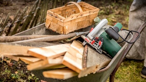 In einer Schubkarre liegen verschiedene Bauwerkzeuge und Holz als Baumaterial. © ndr.de Foto: Udo Tanske