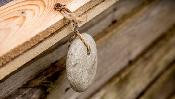 Ein runder Stein hängt als Gewicht am Deckel des Hochbeets. © ndr.de Foto: Udo Tanske