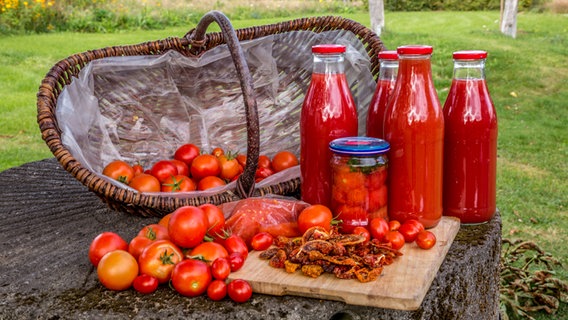Getrocknete, eingekochte, zu Saft verarbeitete und noch in einem  Korb befindliche Tomaten in einem Bild. © NDR Foto: Udo Tanske