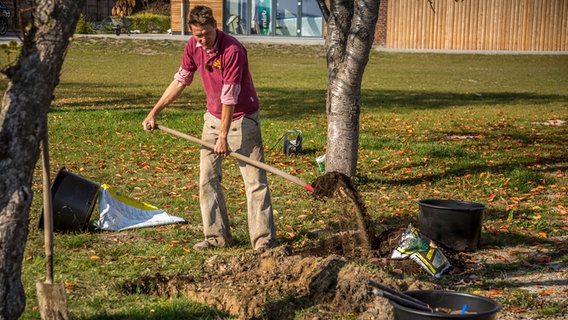 Peter Rasch füllt einen Graben mit Erde. © NDR Foto: Udo Tanske