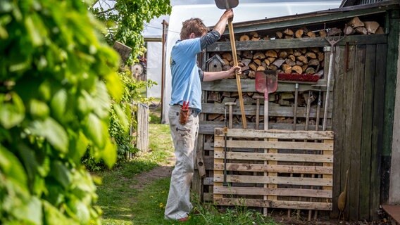 Mann stellt Gartengeräte in eine umgebaute Europalette.  Foto: Udo Tanske