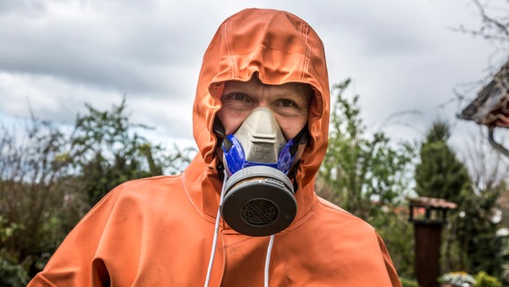 Peter Rasch trägt einen Schutzanzug und Maske © NDR Foto: Udo Tanske