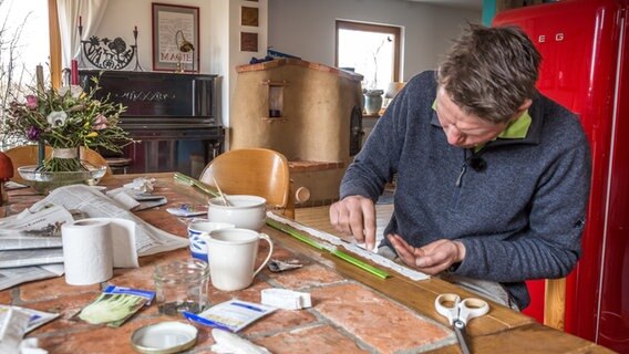 Peter Rasch platziert Samen auf einem selbstgemachten Saatband. © NDR Foto: Udo Tanske