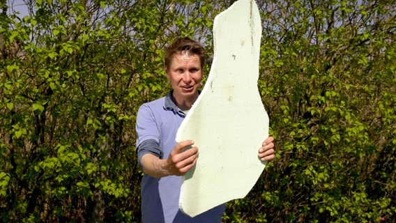 Mann hält eine zugeschnitte weiße Platte hoch. © NDR Foto: Udo Tanke