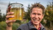 Peter Rasch hält ein Glas mit Urin in der Hand. © NDR Foto: Udo Tanske