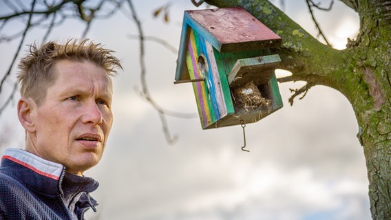 Gartenprofi Peter Rasch steht neben einem Vogelhäuschen, das am Baum hängt © NDR Foto: Udo Tanske
