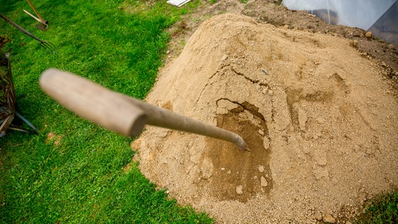Eine Schaufel steckt in einem Sandhaufen © NDR Foto: Udo Tanske