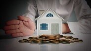 Ein Miniaturhaus und Geld im dunklen Lichteinfall. © Fotolia.com Foto: denphumi