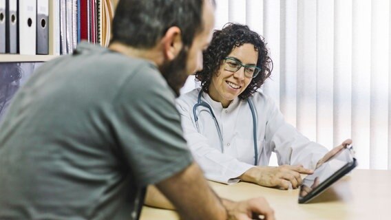 Eine Ärztin im Gespräch mit einem Patienten. © imago images / Westend61 