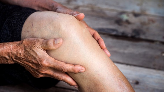 Eine Frau drückt seitlich mit den Händen gegen ihr Knie © Fotolia.com Foto: ojoel