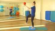 Physiotherapeutin Svea Köhlmoos hält auf einem Bein stehend einen Ball hoch. © NDR 