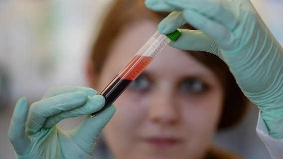 Eine Frau blickt auf die Blutprobe in einem Reagenzglas. © Picture-Alliance / dpa Foto: Patrick Seeger