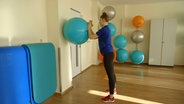 Svea Köhlmoos rollt einen Gymnastikball an der Wand. © NDR 