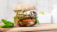 Ein Rindfleisch-Grünkern-Burger auf einem Brett. © NDR Foto: Claudia Timmann