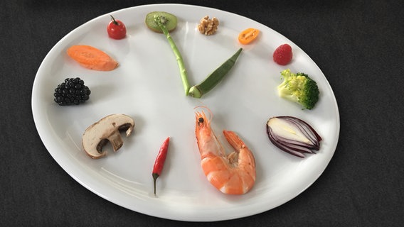 Ein Teller, auf dem aus Gemüsestücken eine Uhr mit Zeigern nachgebildet wurde. © NDR/Katja Gundlach Foto: Katja Gundlach