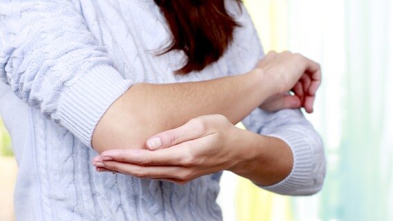 A woman touches her painful elbow.  © Fotolia Photo: Absolute Images