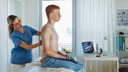 Eine Hautärztin schaut sich den Rücken eines Patienten an. © Colourbox 