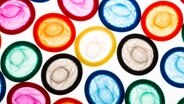 Bunte Kondome liegen auf einer von unten beleuchteten Glascheibe. © Fotolia Foto: rcfotostock
