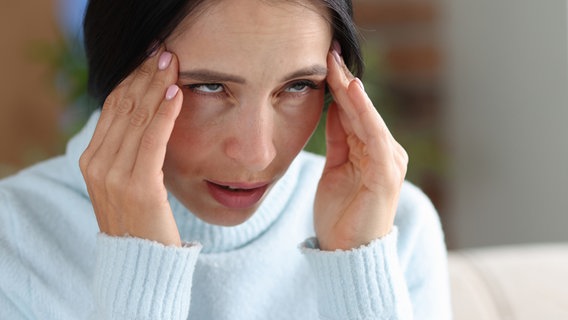 Eine Frau fasst sich an ihren schmerzenden Kopf. © Colourbox 