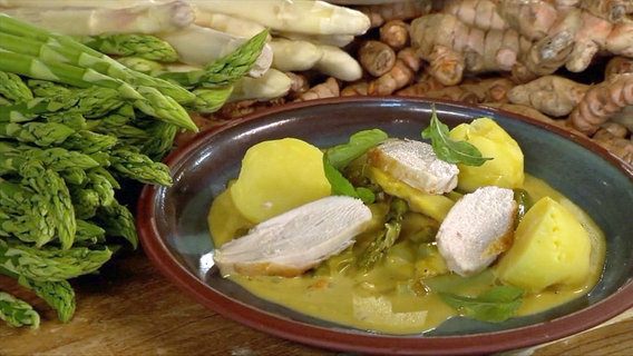 Ein Kurkuma-Spargel-Curry mit Pellkartoffeln und Hühnchen auf einem Teller angerichtet. © NDR Foto: Screenshot NDR