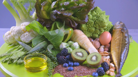 Ein Teller mit Gemüse, Beeren, Kiwi, einem Ei, Fisch, Nüssen und einem Schälchen Öl. © NDR 