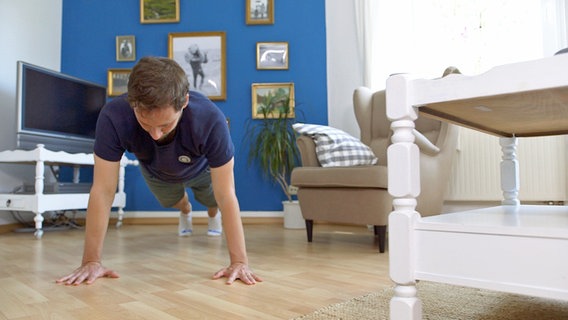 Junger Mann macht im Wohnzimmer Liegestütz. © NDR Foto: Oliver Zydek