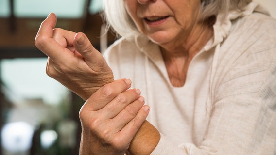 Eine ältere Frau fasst sich an ihr Handgelenk. © Picture Alliance Foto: picture alliance / dpa-tmn | Christin Klose