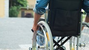 Ein Rollstuhlfahrer ist auf der Straße unterwegs. © Fotolia.com Foto: Minerva Studio