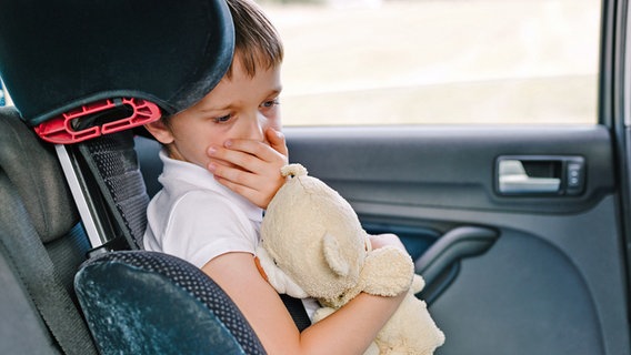 Kind sitzt mit Teddy im Arm im Auto und hält sich die Hand vor den Mund. © Fotolia.com Foto:  Daniel Jędzura