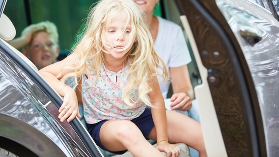 Ein kleines Mädchen klettert aus einem Auto. © picture alliance / Zoonar Foto: Robert Kneschke