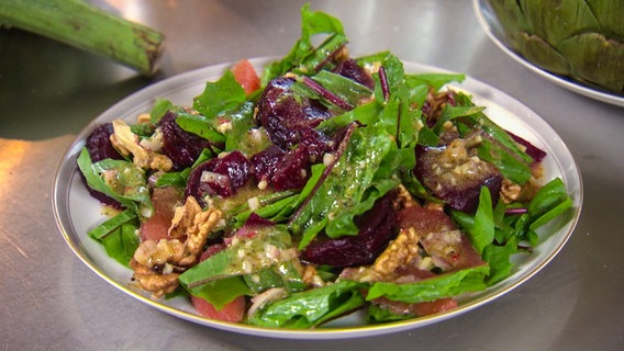 Löwenzahn-Salat mit Roter Bete und Walnüssen auf einem Teller.  