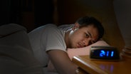 Ein junger Mann liegt schlaflos in seinem Bett. © Colourbox 