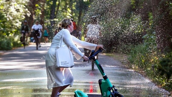 Eine Frau fährt mit einem E-Roller und rutscht aus. © picture alliance 