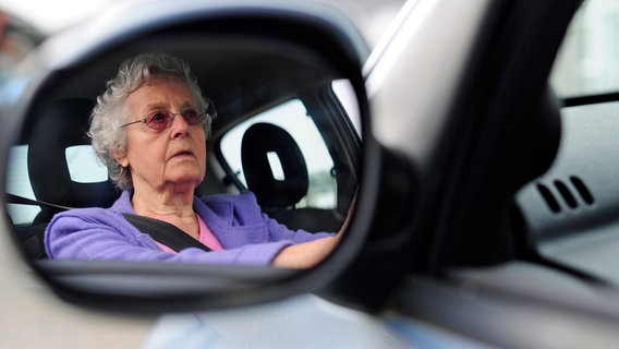 Eine ältere Dame stellt den Seitenspiegel im Auto ein.  Foto: Alexander Körner