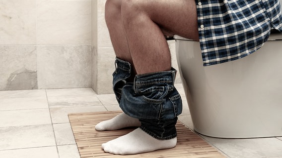 Ein Mann sitzt auf einer Toilette. © colourbox Foto: AtlasStudio