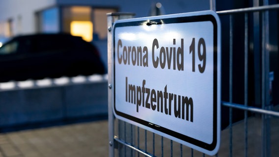 Ein Hinweisschild mit der Aufschrift Corona Covid 19 Impfzentrum hängt an einem Zaun. © Photocase Foto: Michael Bihlmayer