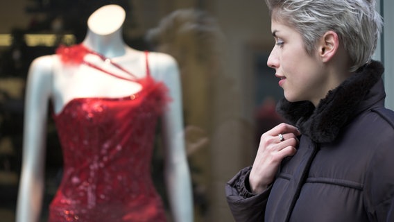 Eine Frau betrachtet ein Kleid an einer Schaufensterpuppe. © Colourbox 