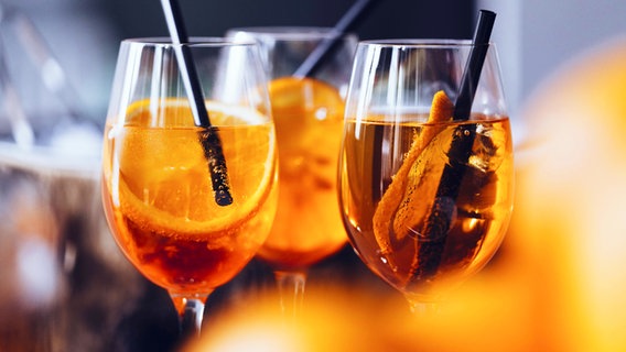 Gläser mit Strohhalmen, Orangenscheiben und einem Aperitif Spritz Getränk. © imago images Foto: fStop Images