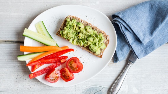 Ein Teller mit Avocado-Brot und Gemüsesticks steht auf einem Tisch. © NDR Foto: Claudia Timmann